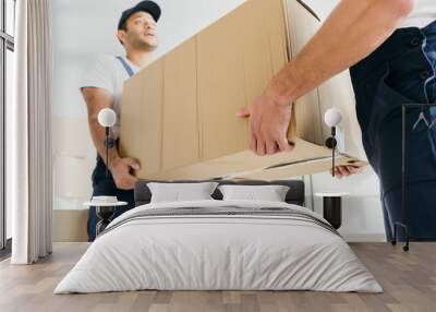 low angle view of multiethnic movers in uniform carrying huge carton box Wall mural