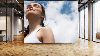 low angle view of young happy woman in crop top against blue sky with clouds, banner Wall mural