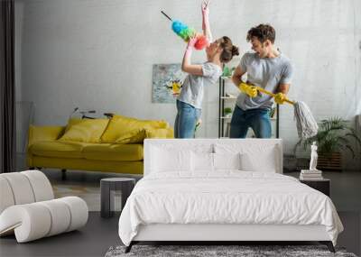 man and woman with household singing while doing spring cleaning in living room Wall mural