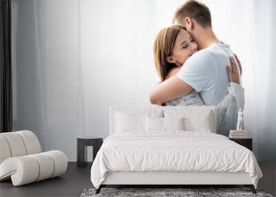 man hugging attractive and smiling woman in apartment Wall mural