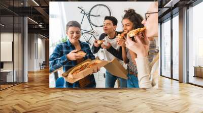 multicultural friends standing and eating pizza Wall mural