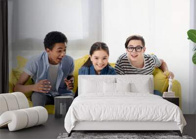 multicultural teen boys supporting friend playing video game at home Wall mural