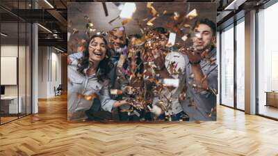 Multiethnic group of cheerful young people standing together and celebrating with confetti Wall mural