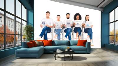 multiethnic group of young people sitting on chairs with crossed legs and reading newspapers isolated on white Wall mural