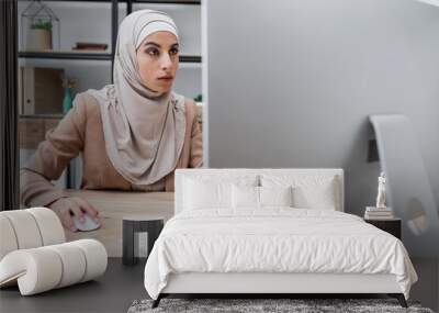 muslim woman working near blurred computer monitor and smartphone with blank screen at home. Wall mural