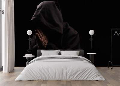 mysterious priest in hooded robe praying isolated on black. Wall mural