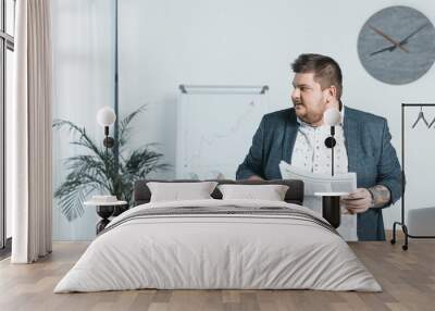 overweight businessman in suit reading newspaper in office Wall mural