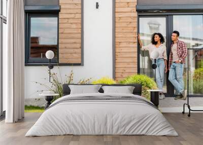 panoramic shot of african american man and woman standing outside near house Wall mural