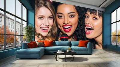 panoramic shot of attractive happy multiethnic girls singing karaoke with microphone, isolated on pink Wall mural