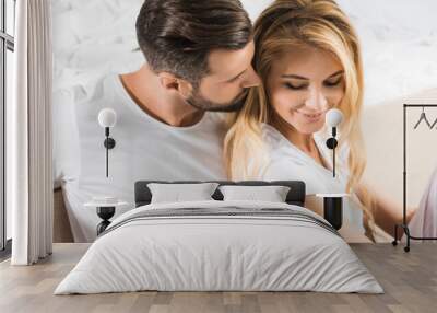 panoramic shot of beautiful couple hugging near bed at home Wall mural