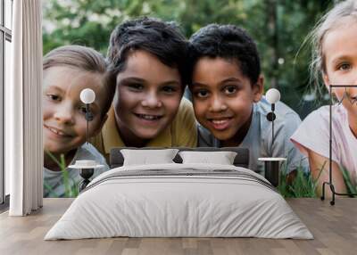 panoramic shot of cute multicultural children lying on grass Wall mural