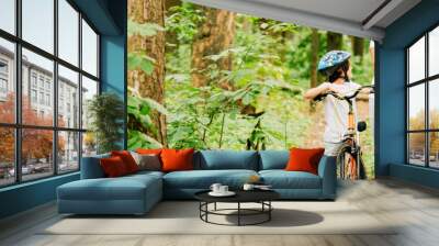 panoramic shot of father and son walking with bicycles in forest Wall mural