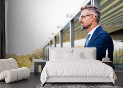 panoramic shot of handsome businessman in formal wear and glasses looking away Wall mural