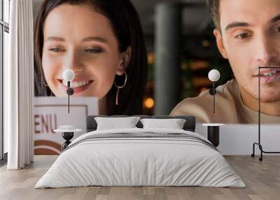 panoramic shot of man and happy woman looking at menus in restaurant Wall mural