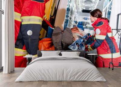 Paramedics transportating patient on gurney in ambulance car Wall mural