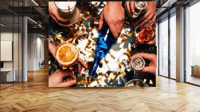 partial view of friends with various alcoholic cocktails playing spin the bottle at table covered by golden confetti Wall mural