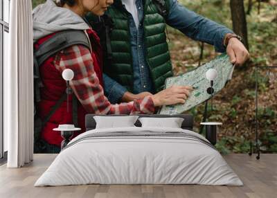 partial view of man and woman looking for destination on map while hiking in forest together Wall mural