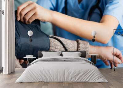 partial view of nurse fixing cuff of tonometer on arm of senior woman on blurred foreground, banner Wall mural