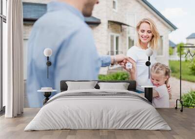 partial view of real estate agent giving key to young woman with daughter in front of new house Wall mural