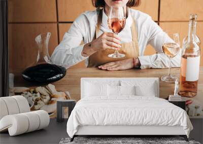 Partial view of sommelier in apron sitting at table and tasting wine Wall mural