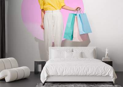 partial view of stylish girl holding colorful shopping bags on white with pink circle Wall mural