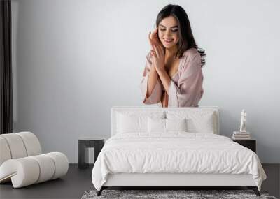 pleased young woman in underwear and silk robe looking down isolated on white Wall mural