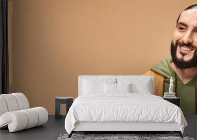 portrait of cheerful and bearded arabic man in casual attire smiling on beige background, banner Wall mural