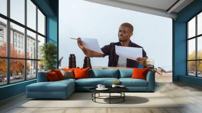 portrait of focused african american photographer looking at photoshoot examples at workplace Wall mural