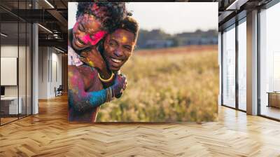 portrait of happy african american couple piggybacking at holi festival Wall mural