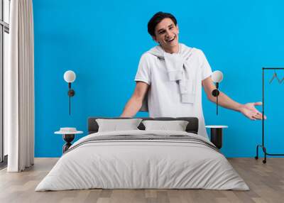 portrait of happy young man with shrug gesture, isolated on blue Wall mural