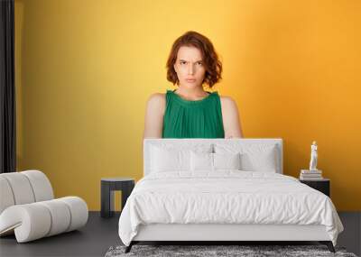 Portrait of offended woman with arms crossed looking at camera isolated on orange Wall mural