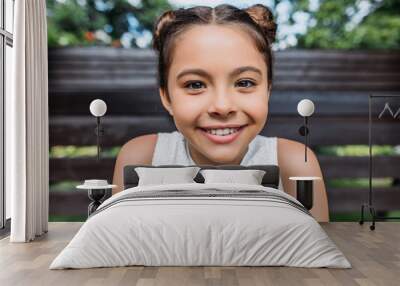 portrait of smiling child looking at camera while sitting on wooden bench Wall mural