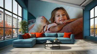 portrait of smiling kid with toy lying on sofa Wall mural