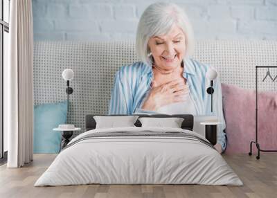 portrait of smiling senior woman reading book while resting on sofa at home Wall mural