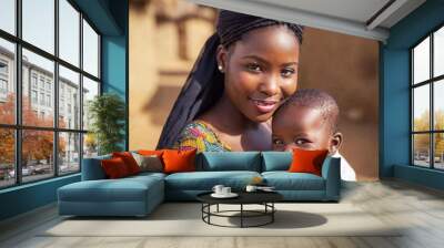 portrait of young african woman with cute little child in traditional village, smiling, looking at camera. Wall mural