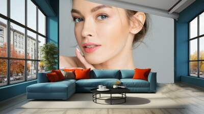 Portrait of young woman with natural visage posing isolated on grey. Wall mural