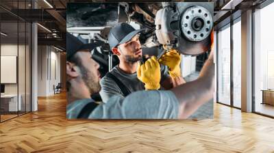 professional amle mechanics repairing car without wheel in auto repair shop Wall mural