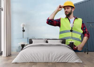 professional confident engineer in safety vest and helmet posing on roof Wall mural