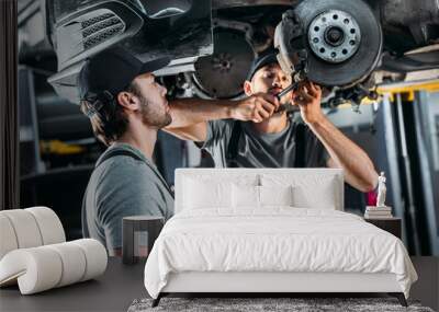 professional mechanics repairing car without wheel in auto repair shop Wall mural