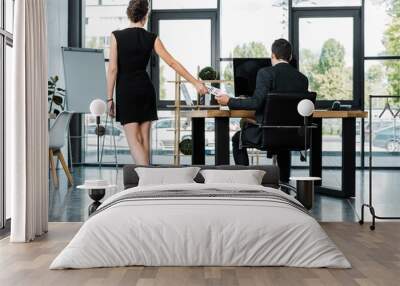 rear view of businesswoman giving call me note to colleague at workplace in office Wall mural