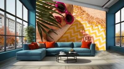 Relaxed young woman in sunglasses lying on yellow towel Wall mural