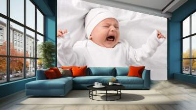 screaming baby in white clothes lying on bed with closed eyes Wall mural