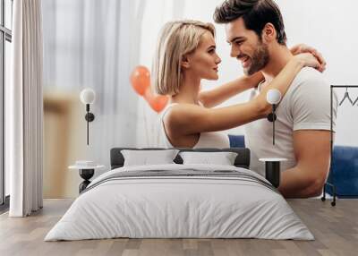 selective focus of attractive girlfriend and handsome boyfriend hugging in bedroom on Valentine's day Wall mural