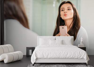 selective focus of beautiful young woman in bathrobe taking selfie with smartphone in bathroom Wall mural