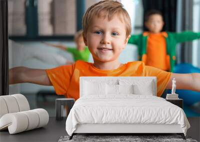 Selective focus of boy smiling and working out with outstretched hands in gym Wall mural