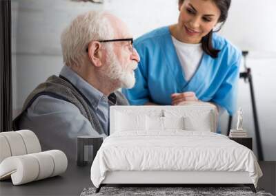 Selective focus of calm gray haired man sitting on couch, near smiling nurse Wall mural