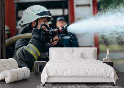 selective focus of firefighter with water hose extinguishing fire on street Wall mural