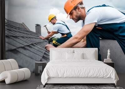 selective focus of handsome handyman repairing roof with coworker Wall mural