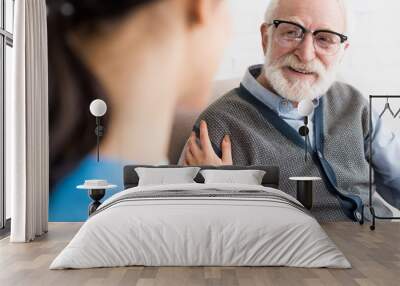 Selective focus of happy grey haired man looking at nurse Wall mural