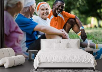 selective focus of happy multicultural men and women in sportswear sitting on fitness mats Wall mural